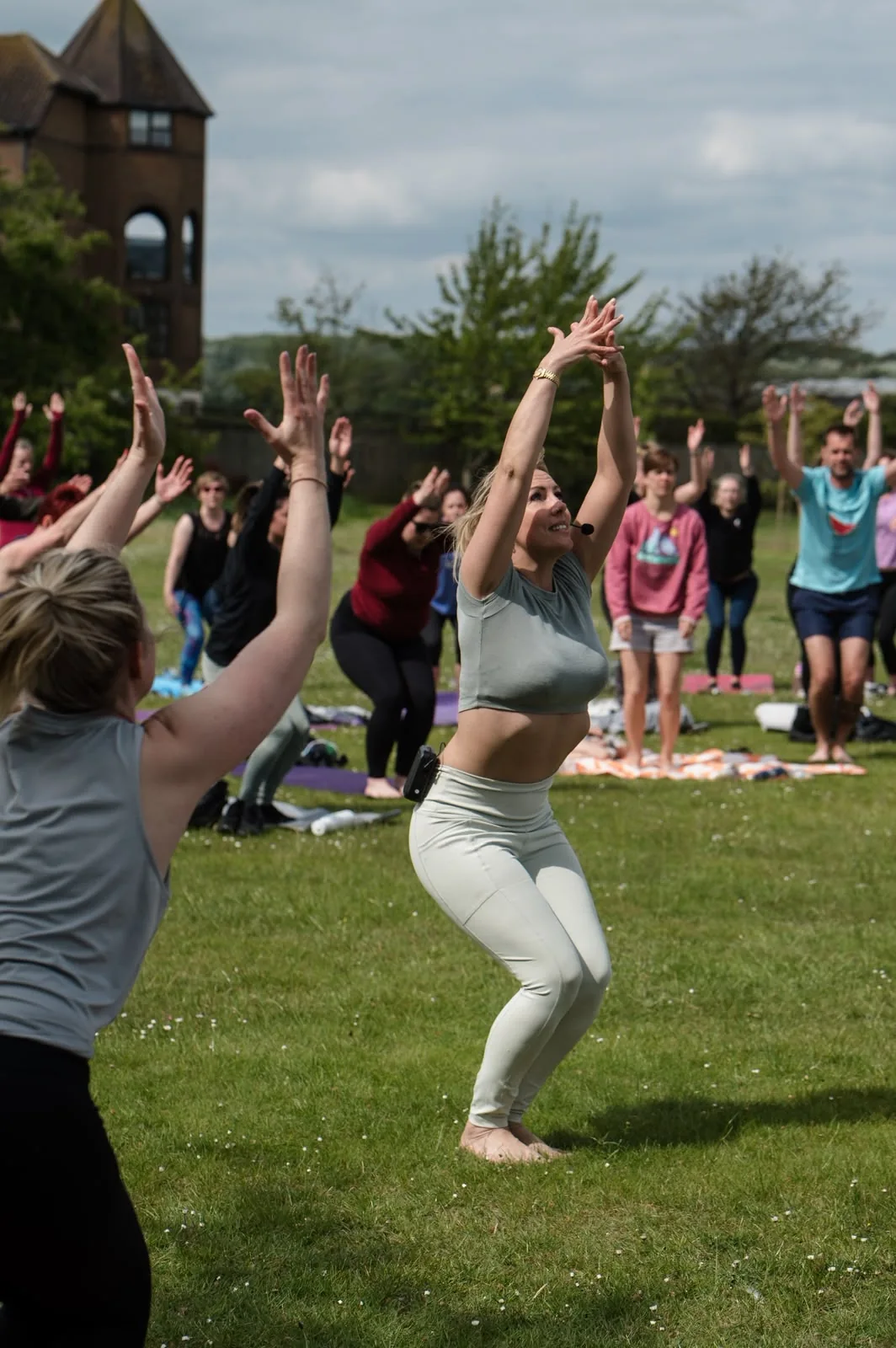 Gem leading a group yoga practice outdoors on the grass