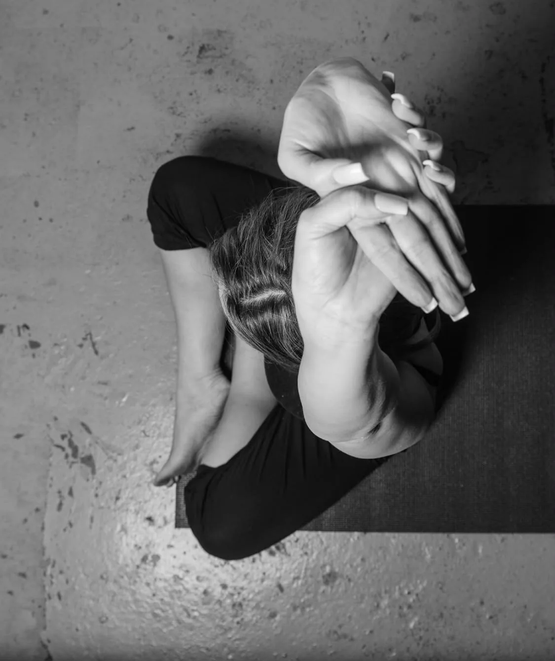 Black-and-white close-up of hands and a foot during yoga practice